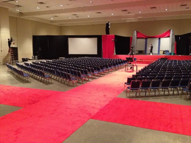 General session setup with red event carpeting, rows of seating, and a draped stage