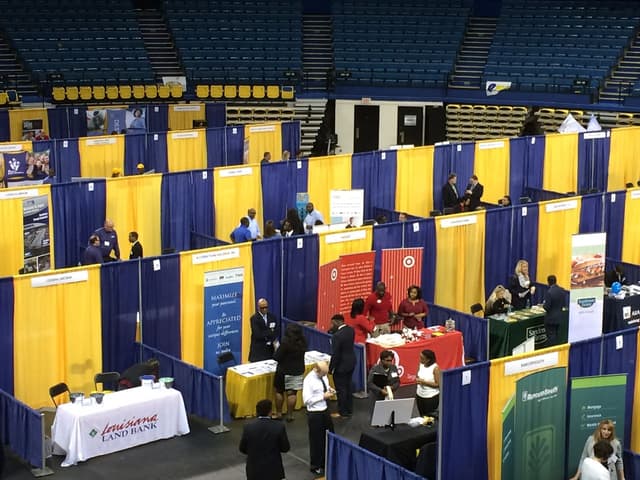 Career fair with rows of blue and gold pipe and drape exhibitor booths in an arena