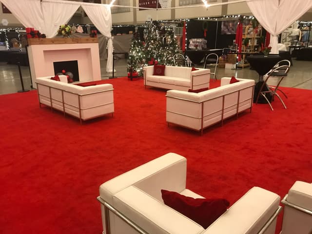 Holiday show lounge with red event carpeting, white leather seating, and decorated trees